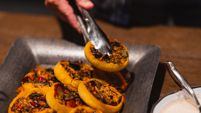 Tongs select a vegan tart from a tray.