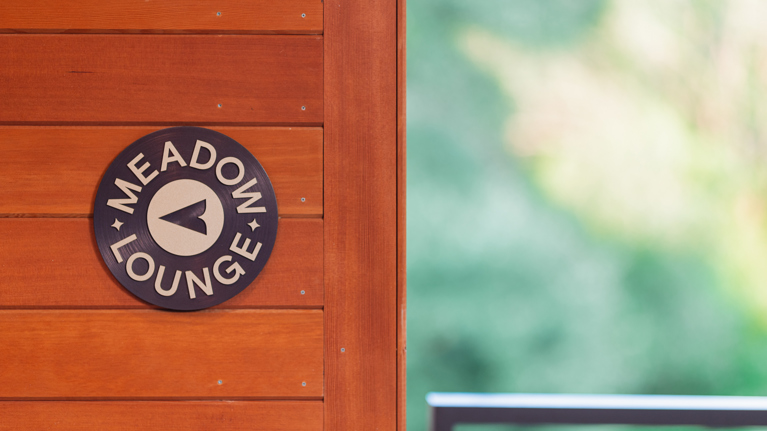 A sign for Meadow Lounge with an arrow pointing left.